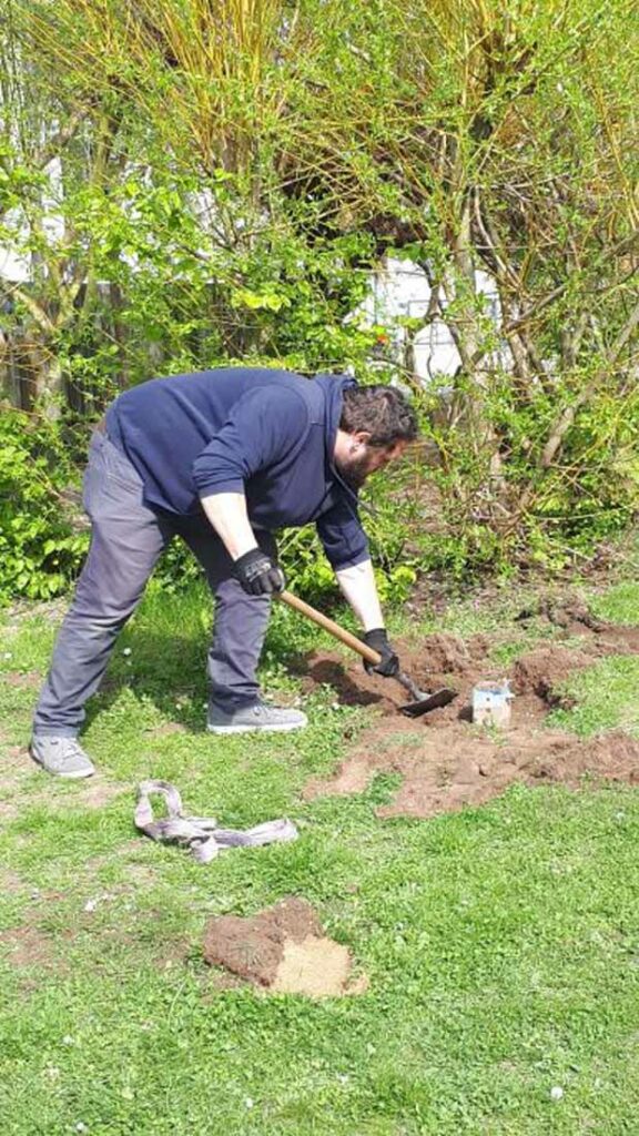 Mann schaufelt mit Gartenspaten ein Loch